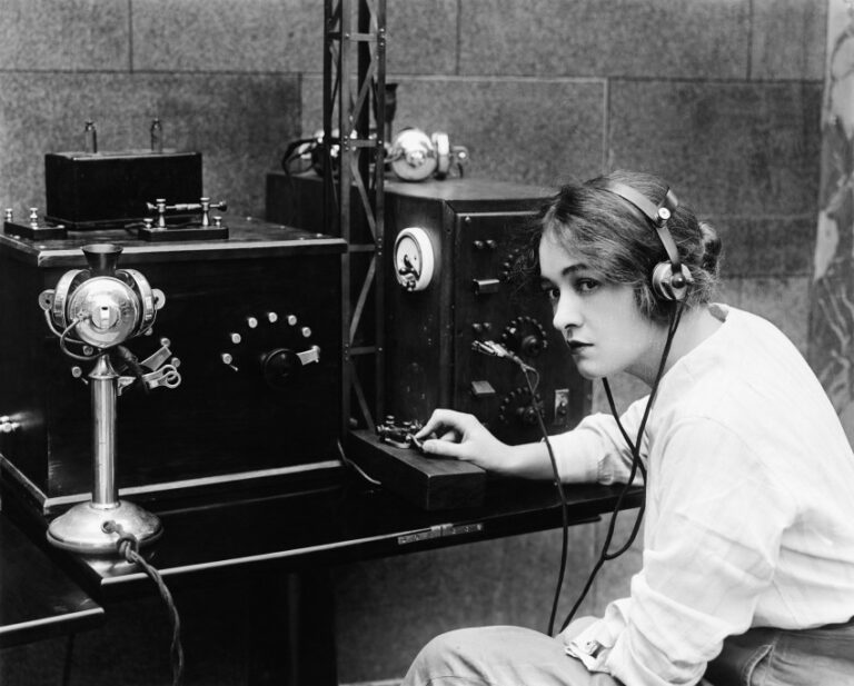 EIn altes Foto von einer Frau vor einem Telegraphen